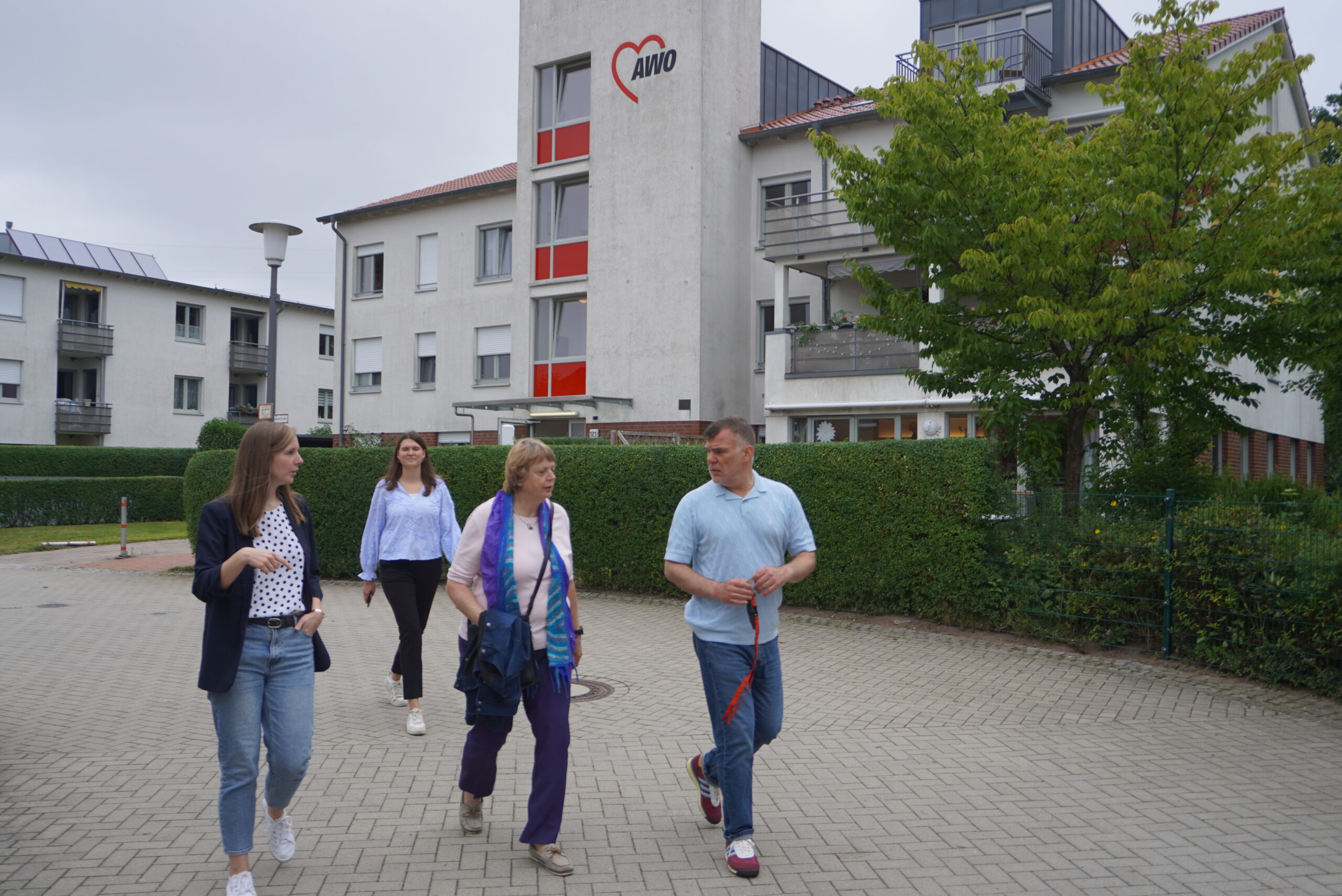 Petra Lotzkat geht mit Mitarbeitenden der AWO Servicewohnanlage Boberger Anger über das Gelände und spricht über die Angebote für Senior*innen.
